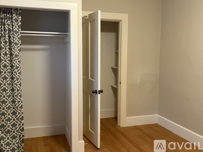 A room with a white door and a grey patterned curtain.