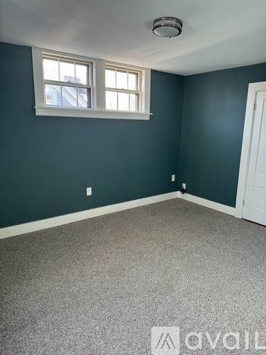 A room with a window and carpeted floor.