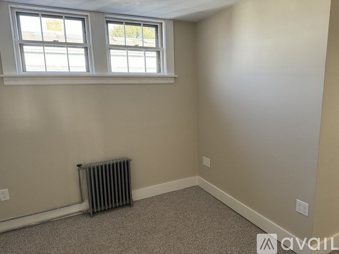 A room with a window and a radiator on the floor.