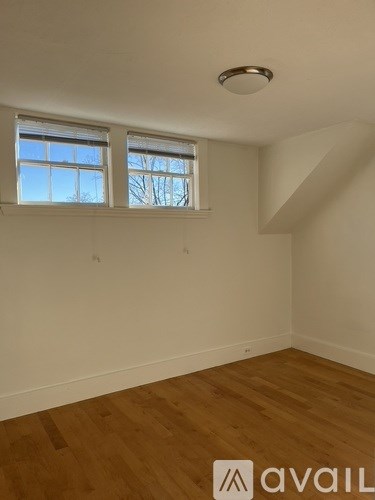 A room with wooden floors and a window with blinds.