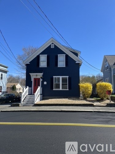 A blue house with a red door and a white window.