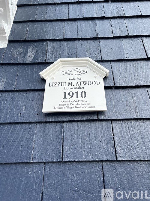 A plaque on a shingled roof reads Lizzie M. Atwood homemaker 1910.