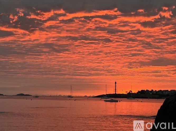 A beautiful sunset over the ocean with a lighthouse in the distance.