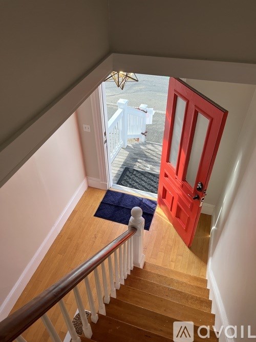 A red door is at the end of a staircase.