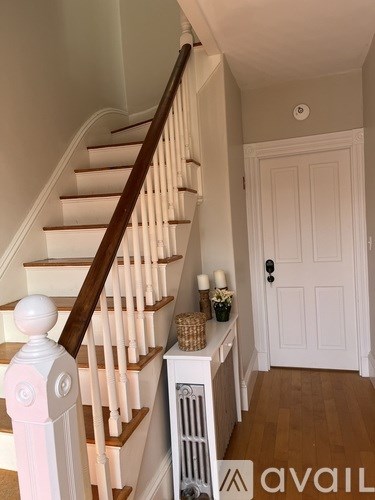 A staircase with a white balustrade and a basket of flowers on the landing.