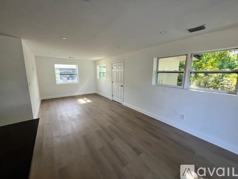 A spacious room with wooden flooring and white walls.