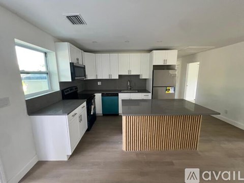 A kitchen with white cabinets and a black countertop.