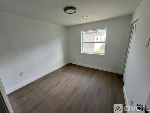 A room with wooden flooring and a window.