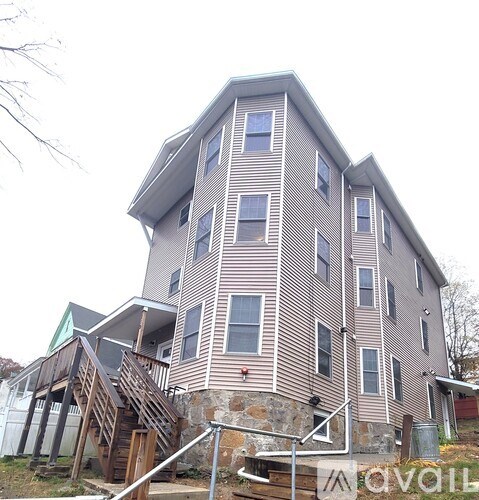 A large house with a stone wall and a wooden staircase.