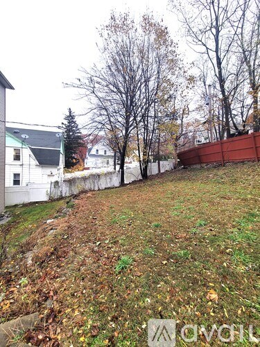 A grassy area with trees and houses in the background.