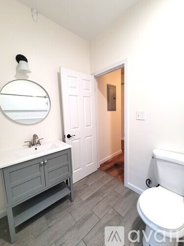 A bathroom with a toilet, sink, and mirror.