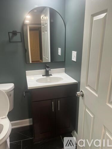 A bathroom with a toilet, sink, and mirror.