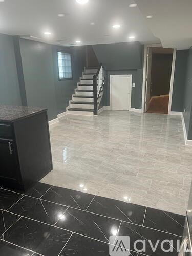 A spacious hallway with a staircase and a black cabinet.