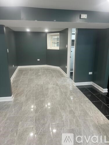 A room with grey tiled flooring and a window.