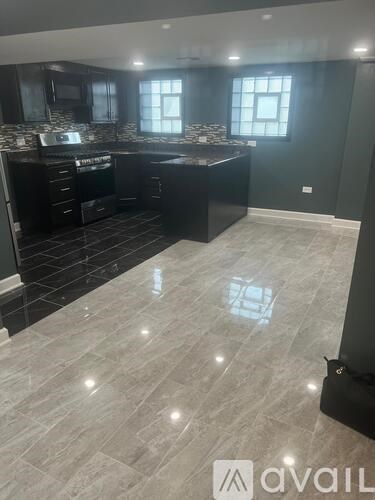 A kitchen with black cabinets and a tiled floor.