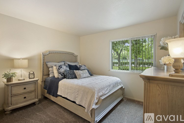 A bedroom with a bed, nightstand, and window.