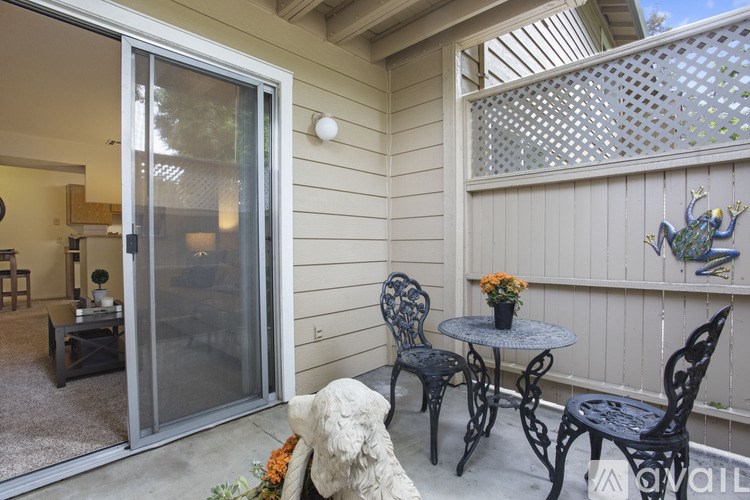A patio with a table, chairs, and a dog statue.