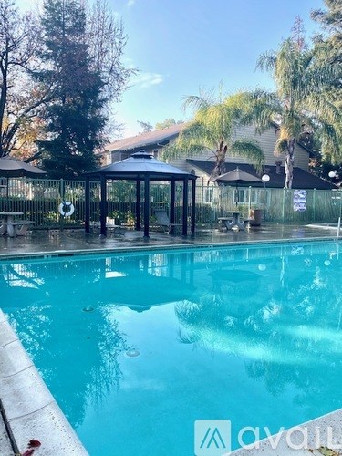A pool with a pavilion and trees in the background.