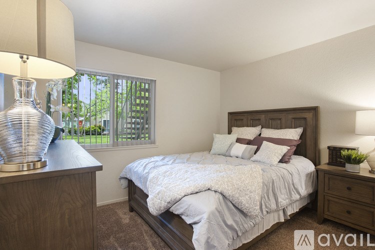 A bedroom with a bed, nightstand, and lamp.