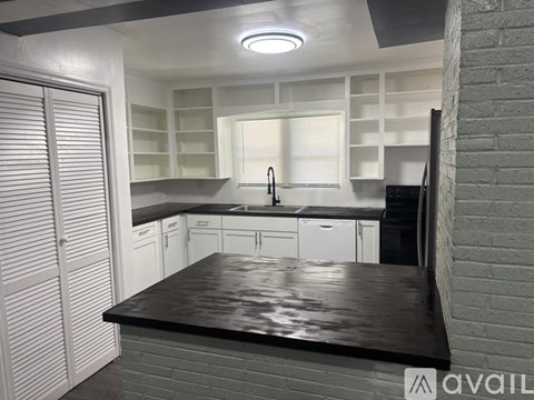 A kitchen with white cabinets and a black countertop.