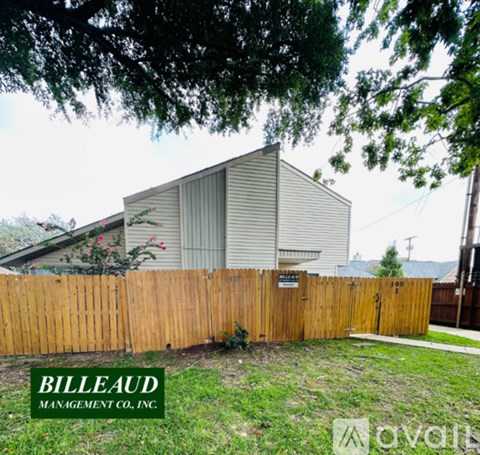 A house with a wooden fence and a sign that says "Billeaud Management Co. Inc."