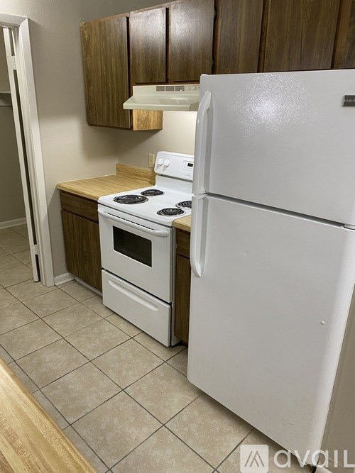 A white refrigerator stands next to a white stove in a kitchen.