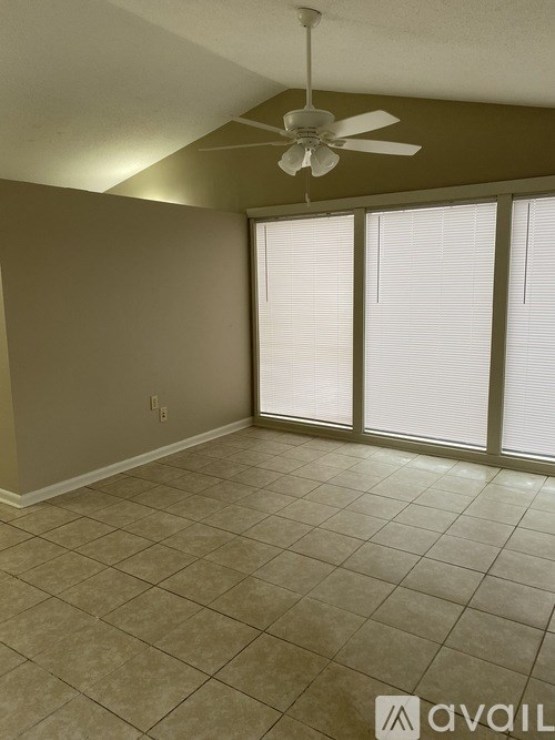A room with a ceiling fan and sliding glass doors.