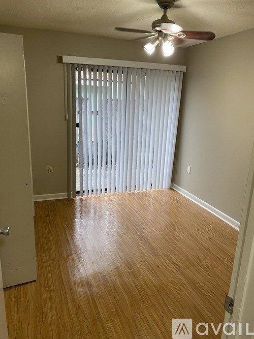A room with a ceiling fan and wooden flooring.