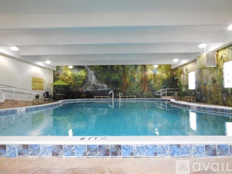 A large indoor swimming pool with a mural of a waterfall on the wall.