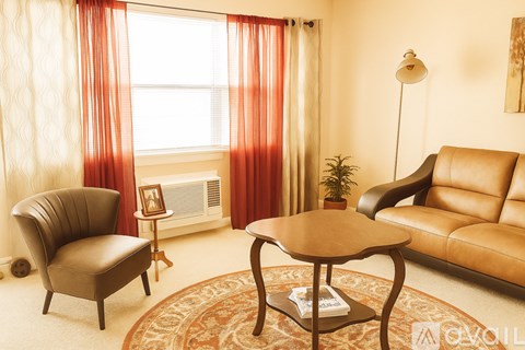 A living room with a brown leather couch, a brown chair, a small table, and a plant.