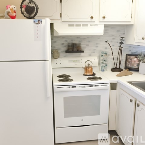 A white kitchen with a fridge, oven, and microwave.