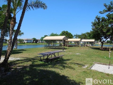 A sunny day at the park with picnic tables and a lake.