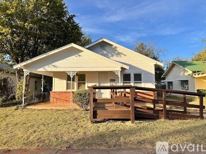 A house with a porch and a fence in front of it.