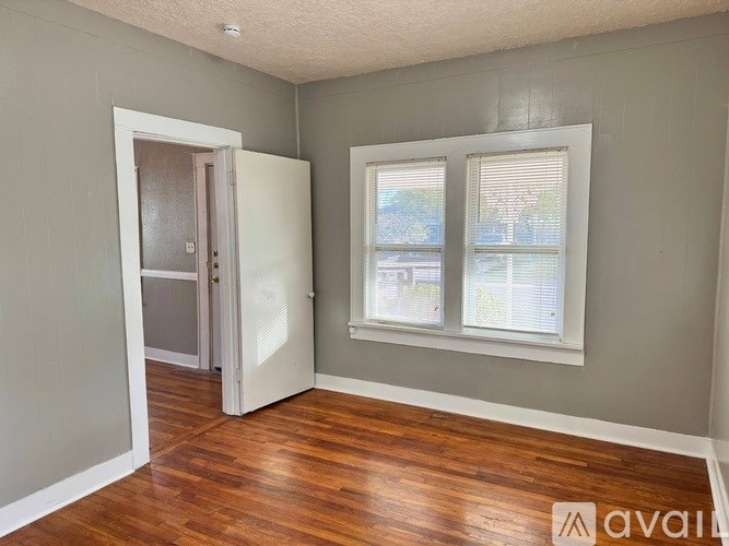 A room with a wooden floor and a window with blinds.