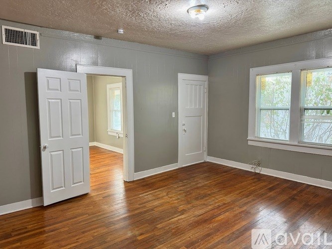 A room with wood flooring and two white doors.