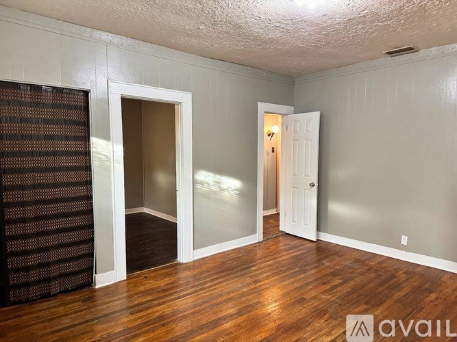 A room with wooden floors and two doors, one of which is open.
