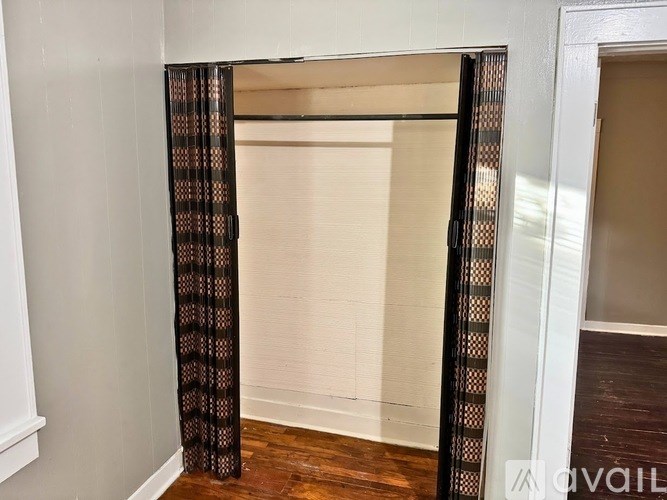 A room with a window covered by a curtain with a pattern of brown and black.