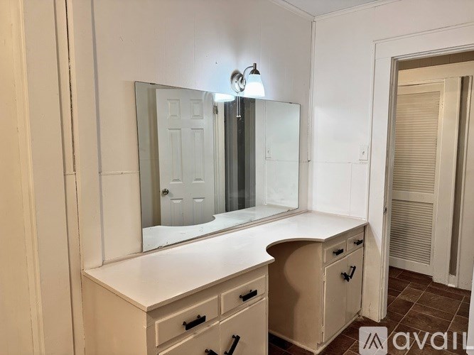 A white vanity with a mirror and lights above it.