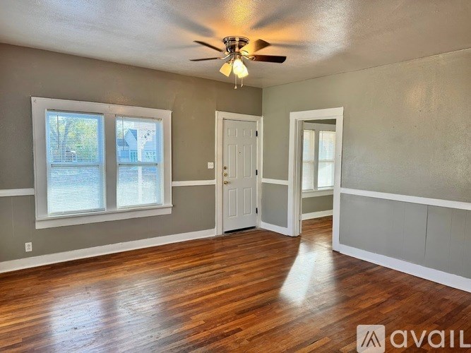 A room with a ceiling fan and wooden flooring.