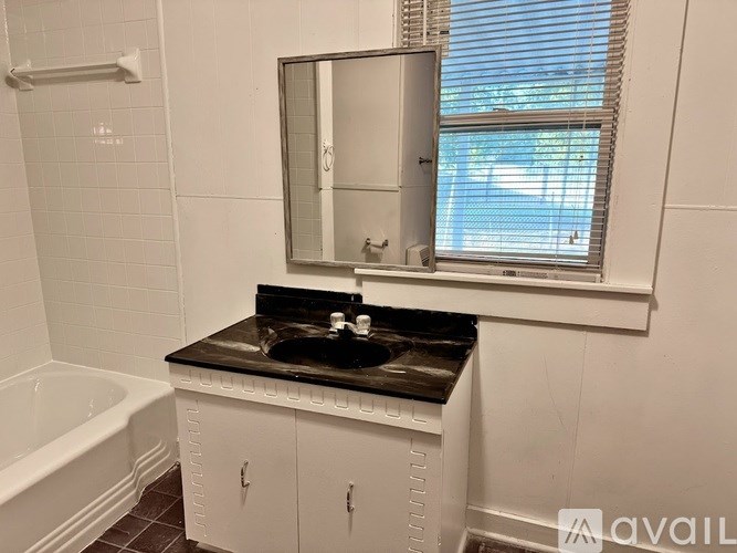 A bathroom with a white cabinet and a black countertop.