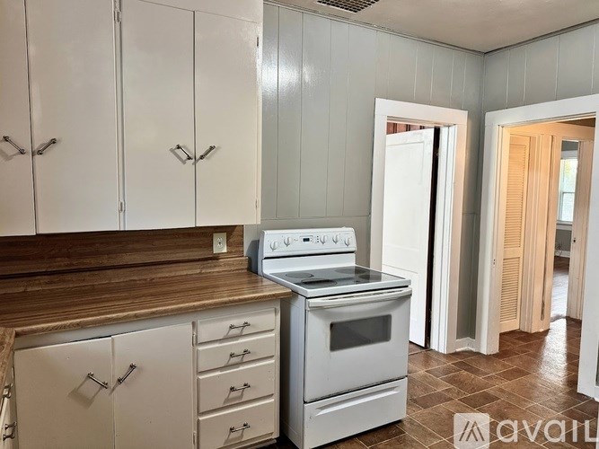 A kitchen with white cabinets and a white stove top oven.