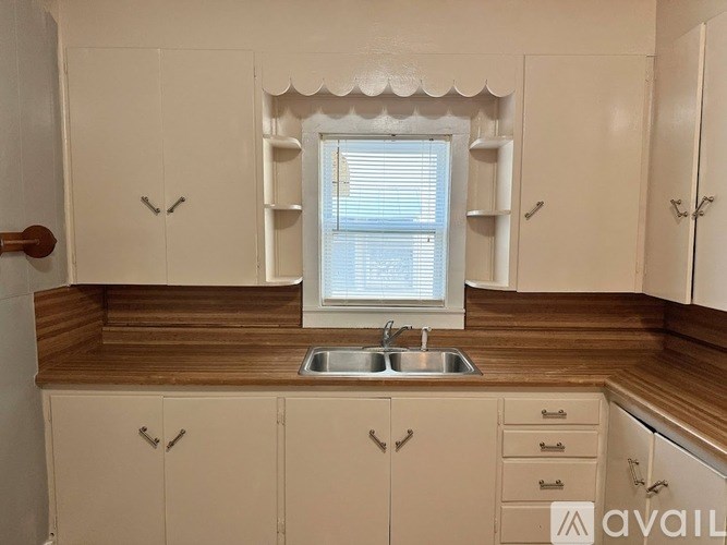 A kitchen with white cabinets and a window above the sink.