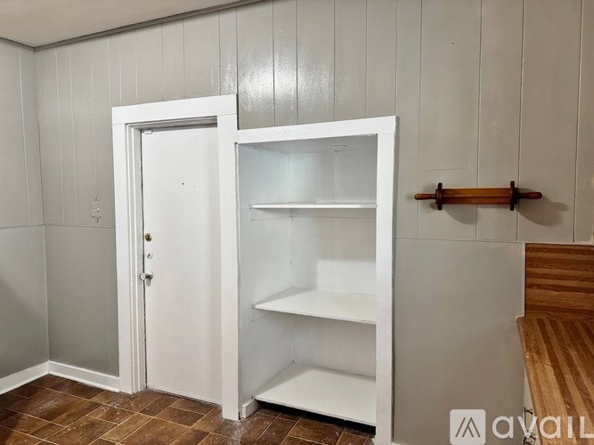 A white door with a shelf is in a room with wooden floors.