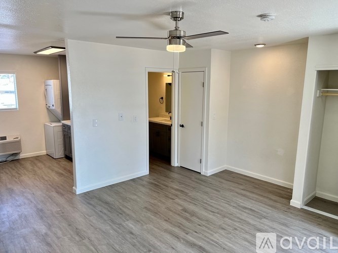 A room with a ceiling fan and light fixture, and a doorway leading to another room.