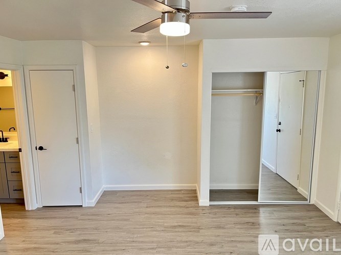 A room with a ceiling fan and a door leading to another room.