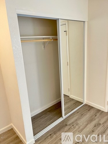A white closet with a mirrored door is open.