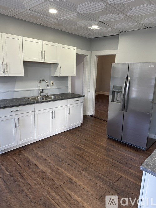 A kitchen with white cabinets and a wooden floor.