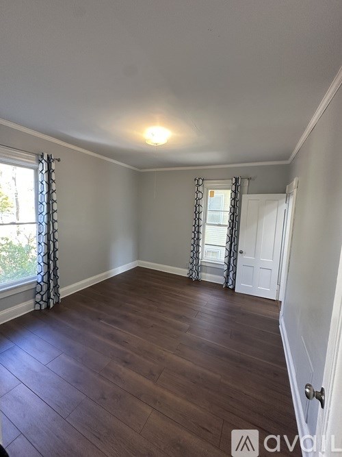 A room with wooden flooring and a window with curtains.
