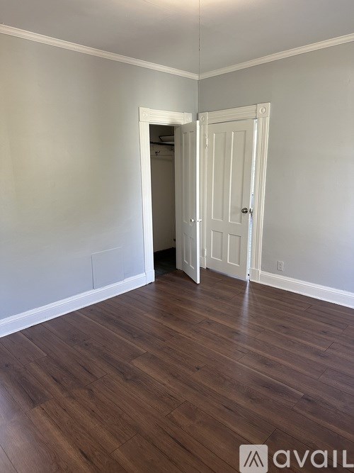 A room with a white door and wooden flooring.