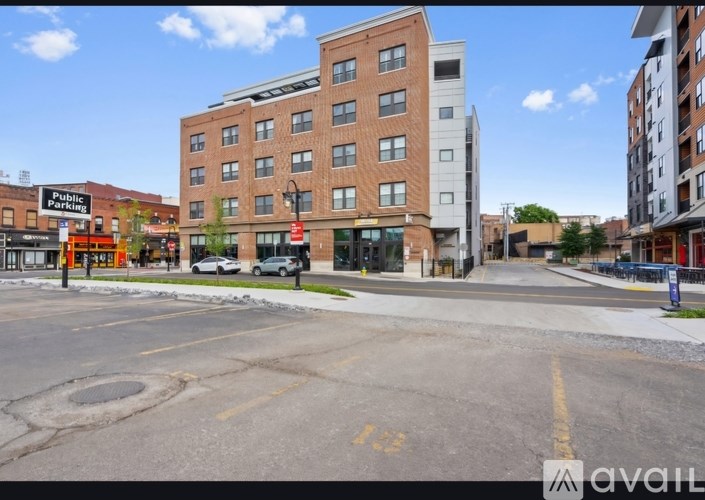 A street view of a city with a building in the background and a car parked on the side of the road.